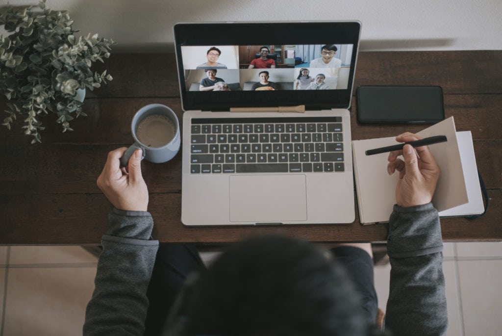 joining virtual call on laptop with coffee and notebook