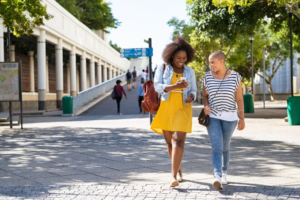 two friends looking at campus maps on phone while walking